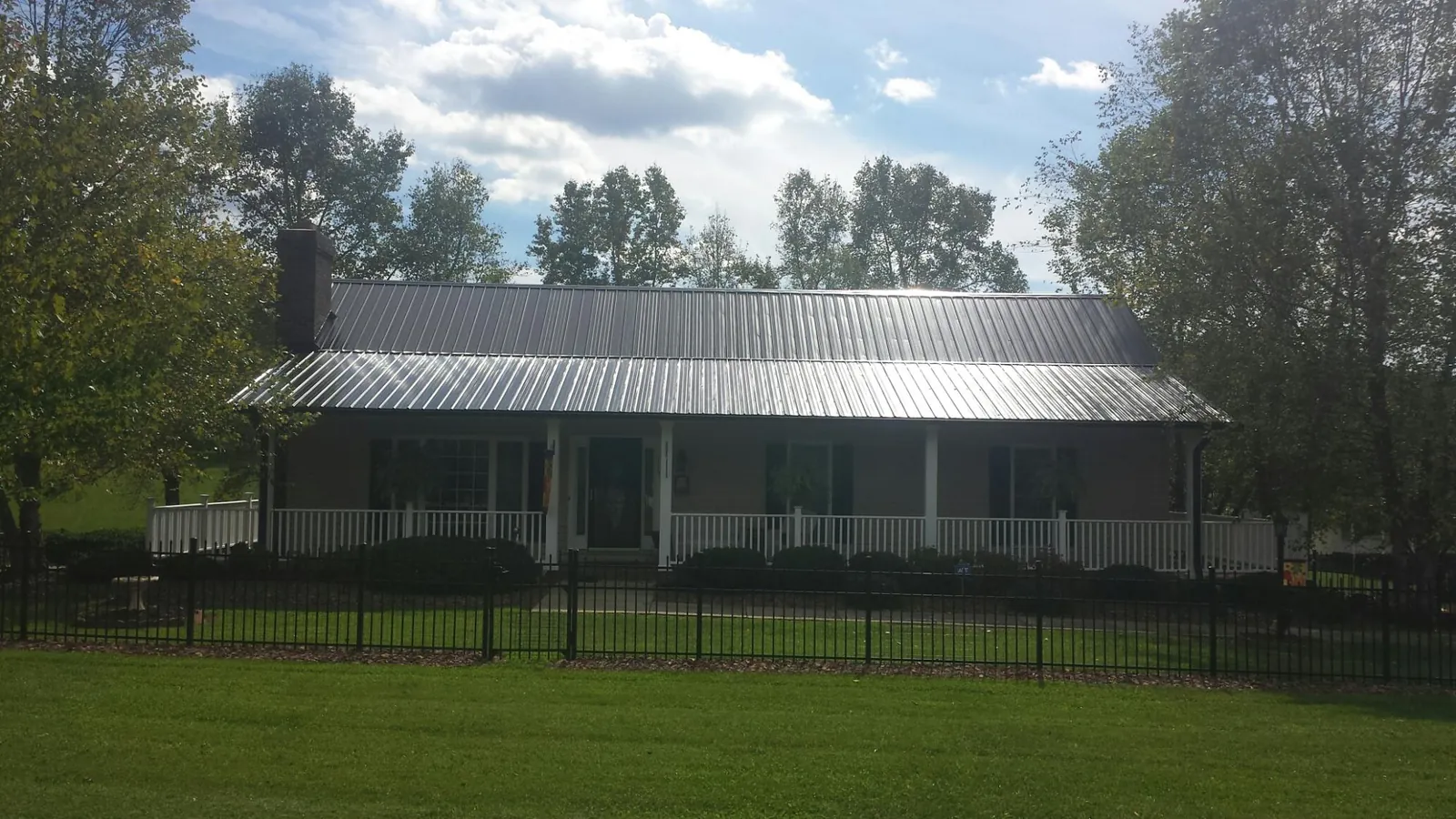 Gray metal roof on a brick ranch with a full width front porch — Gutter Guard Installation work by our crew in Atwood